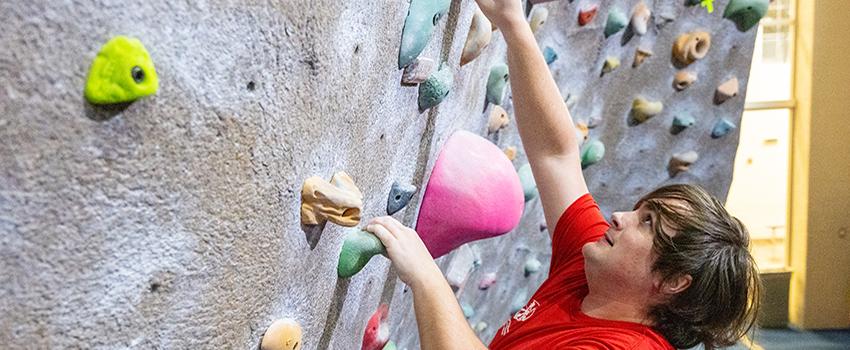 Male student climbing the rock 墙.