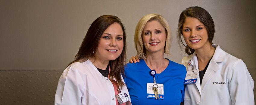 Three 护理实践博士(DNP) nurses with their arms around each other in the Emergency Department